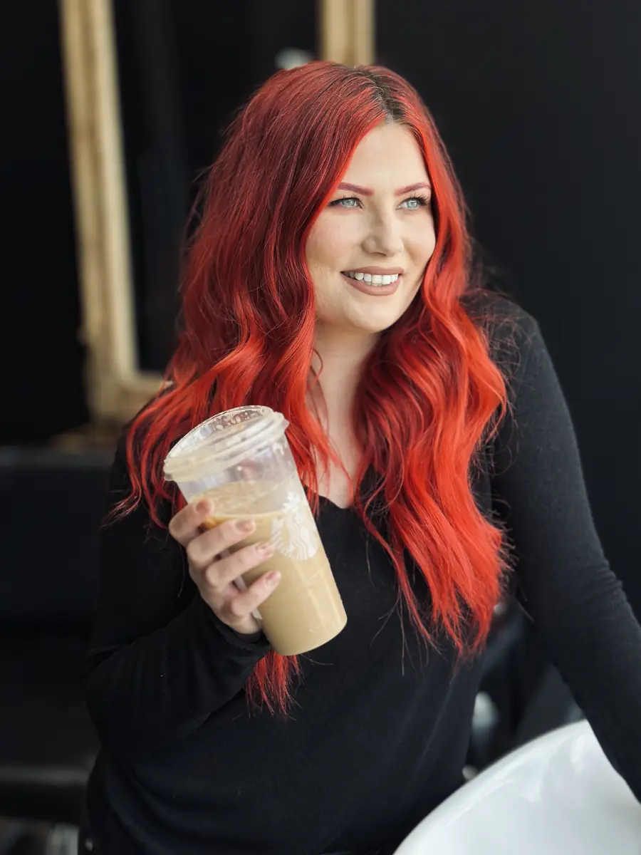 Timillia smiling with an iced coffee in her studio